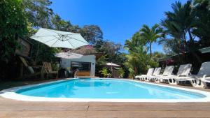 a swimming pool with chairs and an umbrella at Alloro Jungle Villas in Puerto Viejo