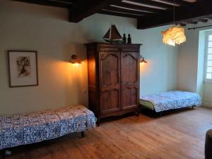 a room with two beds and a wooden cabinet at au coin perdu in Lauzerte