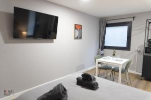 a bedroom with a bed with a tv on the wall at Sierra de Madrid Suites in Galapagar