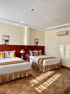two beds in a hotel room with sunlight shining on them at HOÀNG ĐẾ motel in Chau Doc