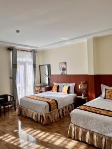 a hotel room with two beds and a window at HOÀNG ĐẾ motel in Chau Doc