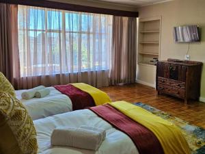 two beds in a room with a large window at Arrosa Guesthouse in Vrede
