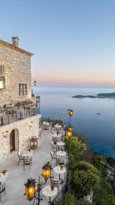 eine Terrasse mit Tischen und Stühlen direkt am Meer in der Unterkunft Chateau Eza in Èze