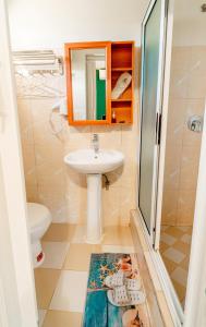 a bathroom with a sink and a toilet and a mirror at Hotel Bom Amigo in Inhambane