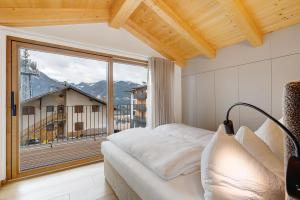 a bedroom with a bed and a large window at Rostrini Family Home Retreat in Cavalese