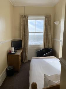 a hotel room with a bed and a window with the ocean at The Lindum in Hastings