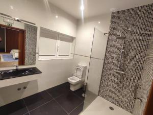 a bathroom with a toilet and a glass shower at NetosResidence in Freixo de Baixo