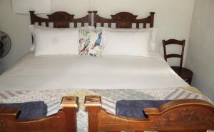 a bedroom with a wooden bed with white sheets and pillows at Honey Farm Country Get Away in Skeerpoort