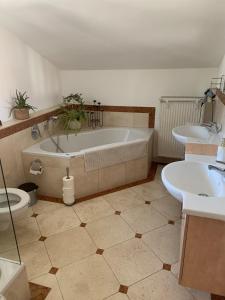 a bathroom with a tub and two sinks and a toilet at Seelenbaumlerin in Schliersee