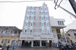 a tall white building with blue windows on a street at Hotel Bhabha in Rajkot