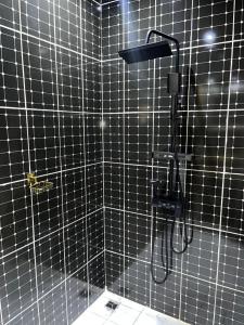 a black tiled shower with a shower head at Maison meublée Odza Yaoundé in Yaoundé