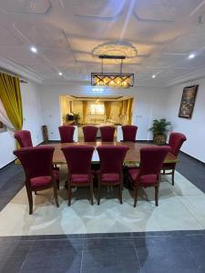 a dining room with a table and red chairs at Maison meublée Odza Yaoundé in Yaoundé +1 photo