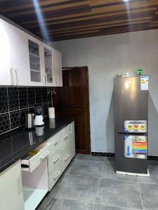 a kitchen with a stainless steel refrigerator and white cabinets at Maison meublée Odza Yaoundé in Yaoundé