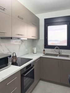 a kitchen with white cabinets and a sink and a window at Ocaso Luxury Apartment in Nea Peramos +15 photos