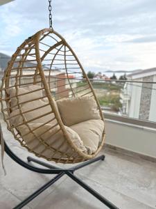 a rattan swing chair on a balcony at Ocaso Luxury Apartment in Nea Peramos
