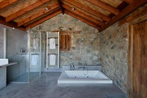 a bathroom with a bath tub in a stone wall at Lyhnos in Askas +21 photos