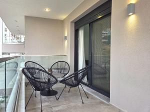 a balcony with three chairs and a table on a balcony at Ocaso Luxury Apartment in Nea Peramos