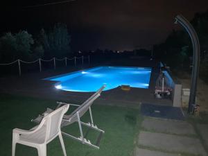 two chairs and a swimming pool at night at Casa Vacanze immersa tra le colline, appartamento, vicinissima al mare e con nuova piscina in Senigallia