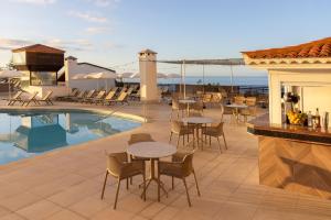 a patio with tables and chairs next to a swimming pool at AluaSoul Orotava Valley - Adults Only in Puerto de la Cruz