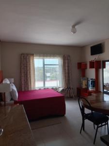 a bedroom with a bed and a table and a window at Hlalanathi Lodge - 9 Shepstone Road, Harding in Harding