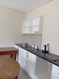 a kitchen with white cabinets and a sink and a table at Hlalanathi Lodge - 9 Shepstone Road, Harding in Harding +26 photos