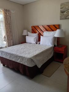 a bedroom with a bed with a wooden headboard at Hlalanathi Lodge - 9 Shepstone Road, Harding in Harding