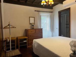 a bedroom with a bed and a dresser and a window at Quinta do Rossio, Rural Tourism in Biscoitos