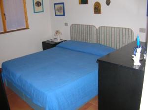 a bedroom with a blue bed and a desk at Villa Silvia in Costa Rei