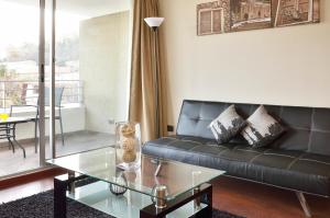 uma sala de estar com um sofá preto e uma mesa de vidro em Norus Providencia em Santiago