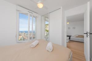 a white bedroom with two towels on a bed with windows at Haut de Monaco - Vue panoramique mer et ville - FE in Beausoleil