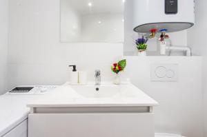 a white sink in a white kitchen with flowers at Haut de Monaco - Vue panoramique mer et ville - FE in Beausoleil +12 photos