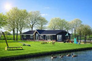 a house with a playground and ducks in the water at Group accommodation De Beemster with Sauna | 14 persons in West-Graftdijk