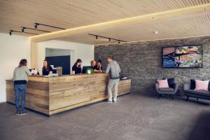 a group of people standing at a reception desk at Gruppenhaus Frutigresort in Frutigen