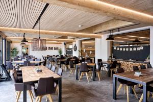 a restaurant with wooden ceilings and tables and chairs at Gruppenhaus Frutigresort in Frutigen