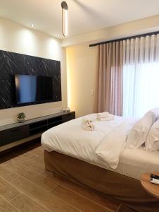 a bedroom with a large bed with a flat screen tv at Olive City Suites in Larisa