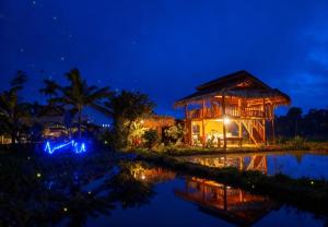 a resort at night with a reflection in the water at padi bungalow in Tetebatu