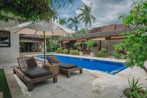 an umbrella and chairs next to a swimming pool at Frangipani Beach Hotel in Lovina