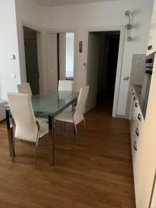 a dining room with a glass table and white chairs at Appartamento Solution Garibaldi in Marina di Ravenna