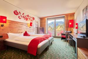 a hotel room with two beds and a desk and a television at Hotel Oberstdorf in Oberstdorf