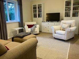 a living room with white furniture and a flat screen tv at Chestnut Cottage New Forest in Brockenhurst