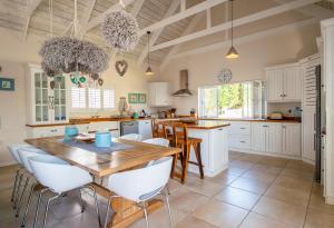 a kitchen with a wooden table and white chairs at Beach House in Struisbaai