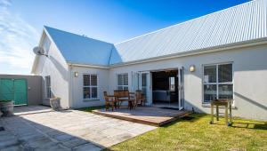 a white house with a table and chairs on a patio at Beach House in Struisbaai