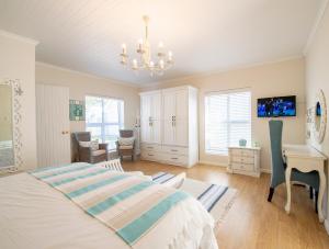 a bedroom with a bed and a desk and a chandelier at Beach House in Struisbaai +30 photos