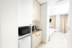 a white kitchen with a microwave and a television at Bella Apartments Brno in Brno