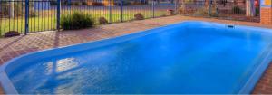 a blue swimming pool next to a fence at Macquarie Valley Motor Inn in Warren