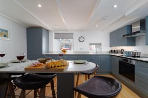 a kitchen with blue cabinets and a table with glasses of wine at Karibu - Boutique Cottage with Parking - Short walk to Beach in St Ives