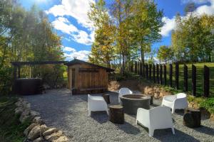 a patio with white chairs and a wooden building at Evergreen Retreat in Râșca