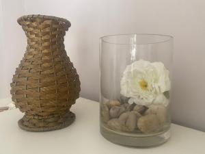 a glass vase with a white flower in it next to a basket at Parva Domus Intera casa indipendente in centro in Modica