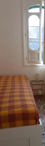 a bedroom with a bed with a striped comforter and a window at Parva Domus Intera casa indipendente in centro in Modica