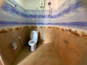 a bathroom with a toilet and a painting on the wall at Happiness Cottage in Ella